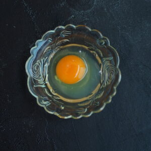 A cracked sous vide pasteurized egg in a clear bowl