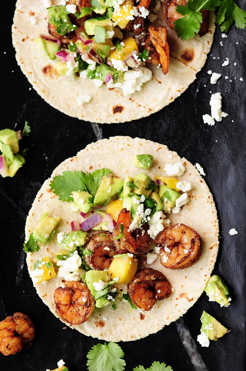 Shrimp tacos made with a homemade blackened seasoning mix, topped with refreshing mango avocado salsa and feta cheese. Yum!