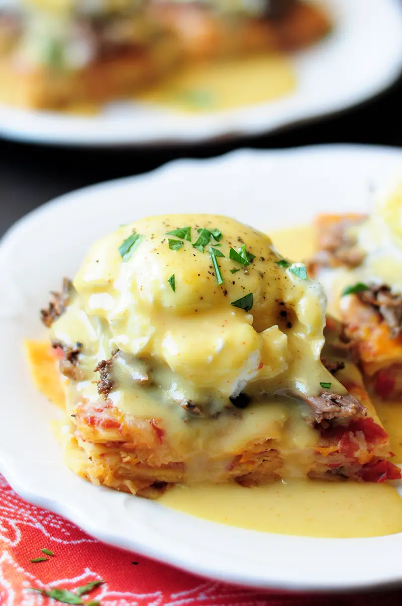 This is a unique Eggs Benedict recipe with slow cooked barbacoa and a green chili hollandaise served on a chilaquiles base.