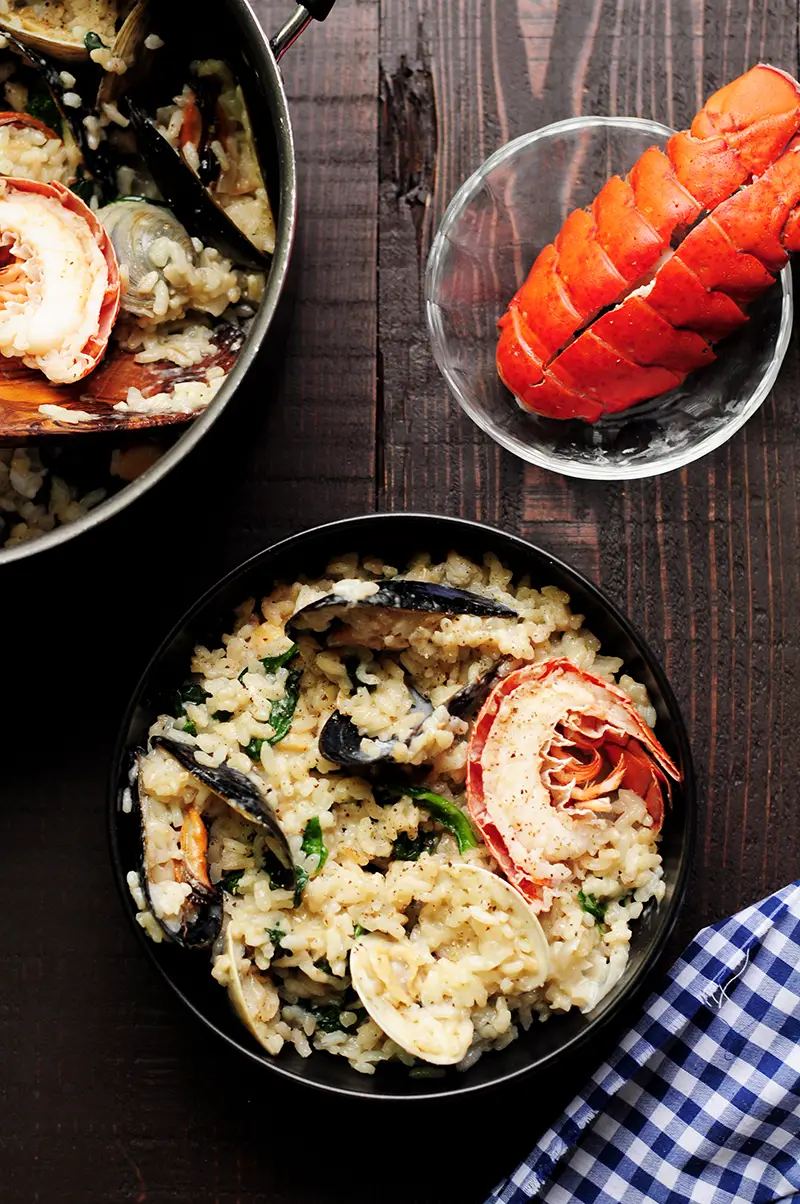 Creamy seafood risotto recipe dedicatedly simmered in lobster stock and heavy cream with clams, mussels, bay scallops, lobster tails, and spinach. It's a perfect date-night-in dinner or for any special occasions.