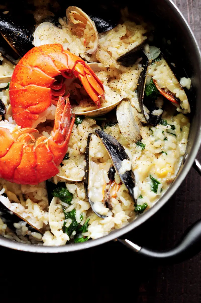 Creamy seafood risotto recipe dedicatedly simmered in lobster stock and heavy cream with clams, mussels, bay scallops, lobster tails, and spinach. It's a perfect date-night-in dinner or for any special occasions.