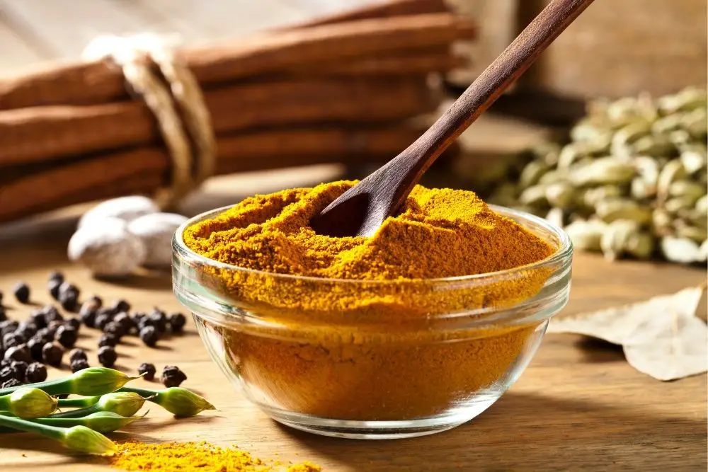 Curry Powder in a clear bowl with a spoon in it