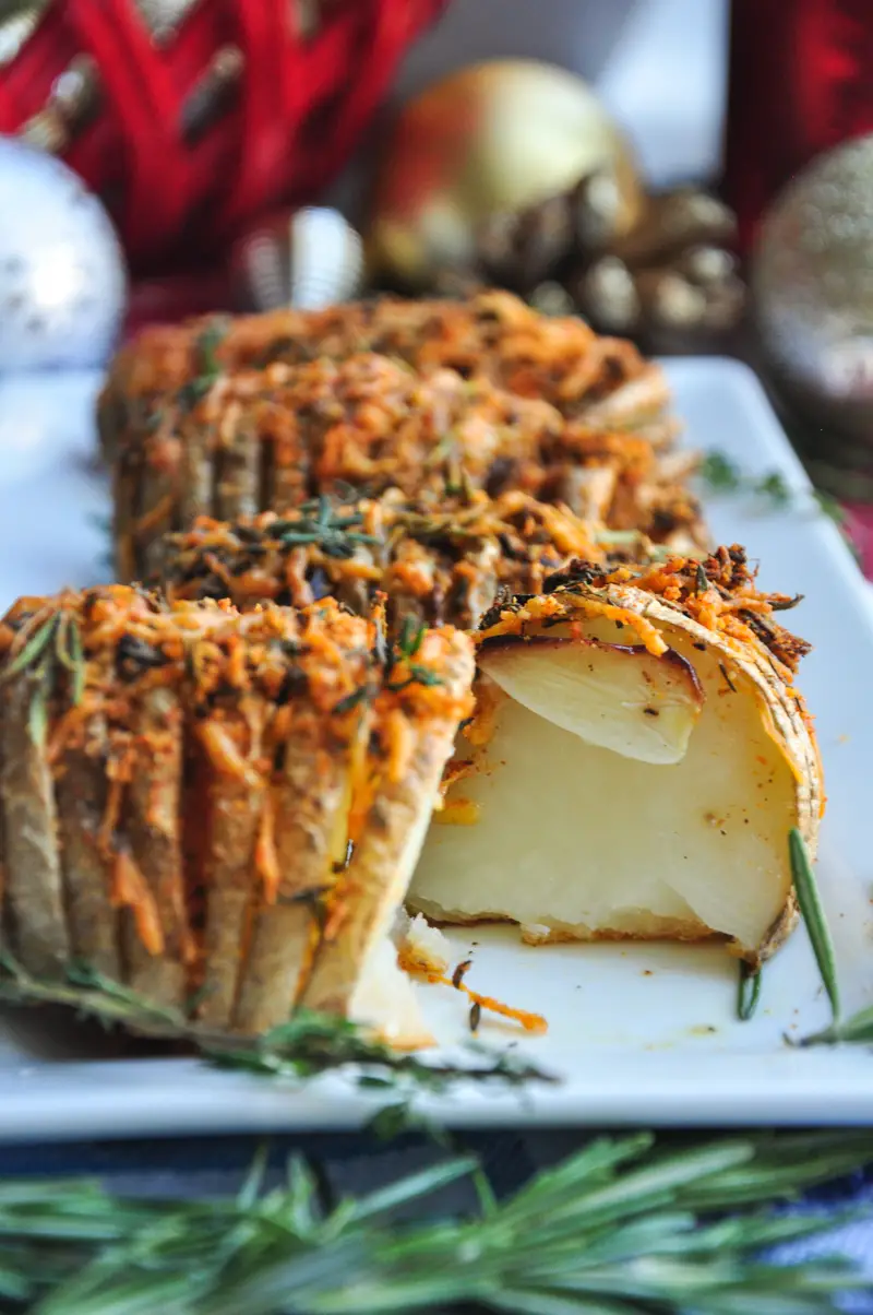 Perfectly baked hasselback potatoes with garlic slices in between, brushed with infused butter, topped with cheddar, parmesan, and three freshly chopped herbs.