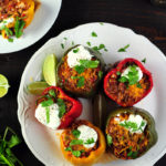 Stuffed peppers with taco-flavored ground beef, onion, tomatoes and cheddar cheese topped with avocado slices, fresh cilantro, and sour cream.
