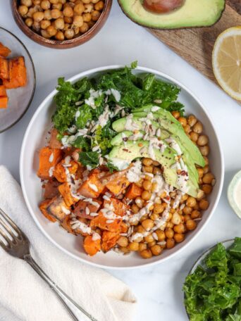 Crispy chickpea salad with kale features harissa-roasted chickpeas, sweet potatoes, and massaged kale in a vibrant, vegan bowl.
