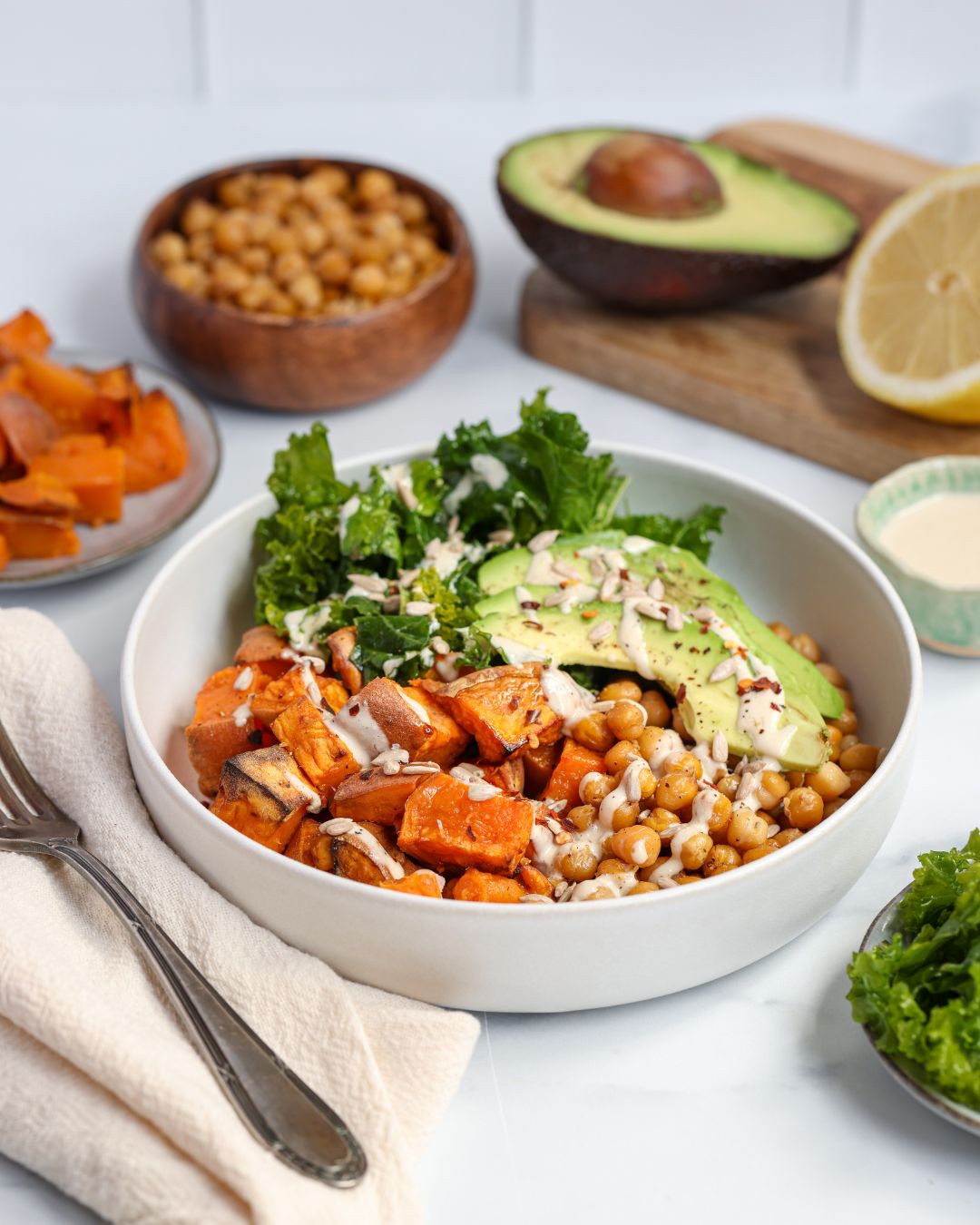 Crispy chickpea salad with kale features harissa-roasted chickpeas, sweet potatoes, and massaged kale in a vibrant, vegan bowl.