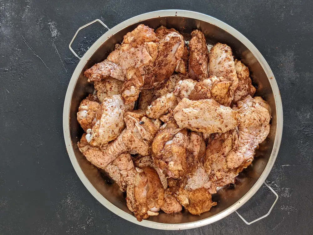 Seasoned chicken wings in a shallow metal container