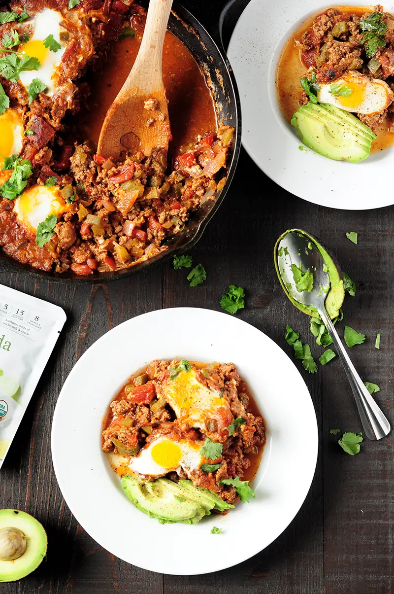 Easy 7-ingredient Shakshuka recipe simmered in a tangy, aromatic red chili sauce with rich notes of cocoa, smoked paprika, and ancho chili.