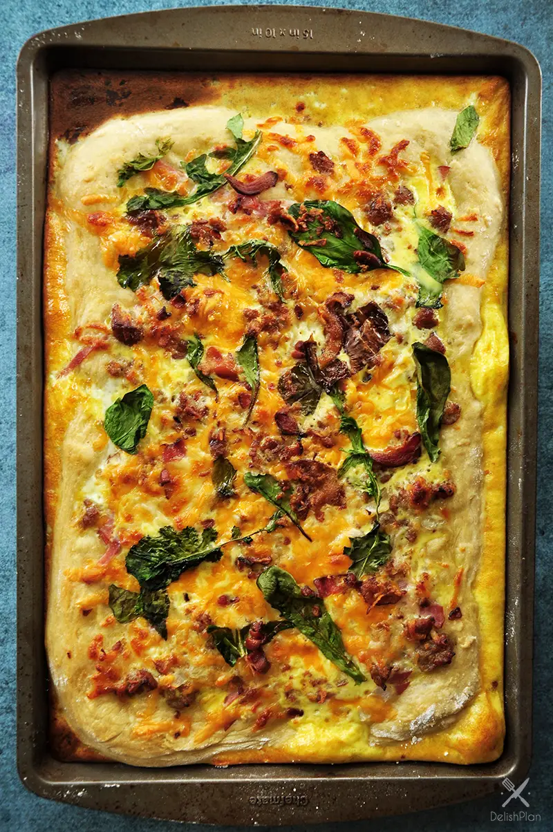 Sheet pan breakfast pizza recipe incorporates your favorite breakfast ingredients like bacon and eggs, plus onions and greens for a balanced one-pan meal.