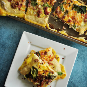 Sheet pan breakfast pizza recipe incorporates your favorite breakfast ingredients like bacon and eggs, plus onions and greens for a balanced one-pan meal.