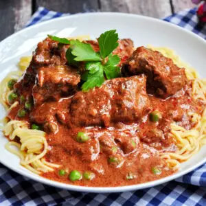 Slow cooker goulash served over egg noodles