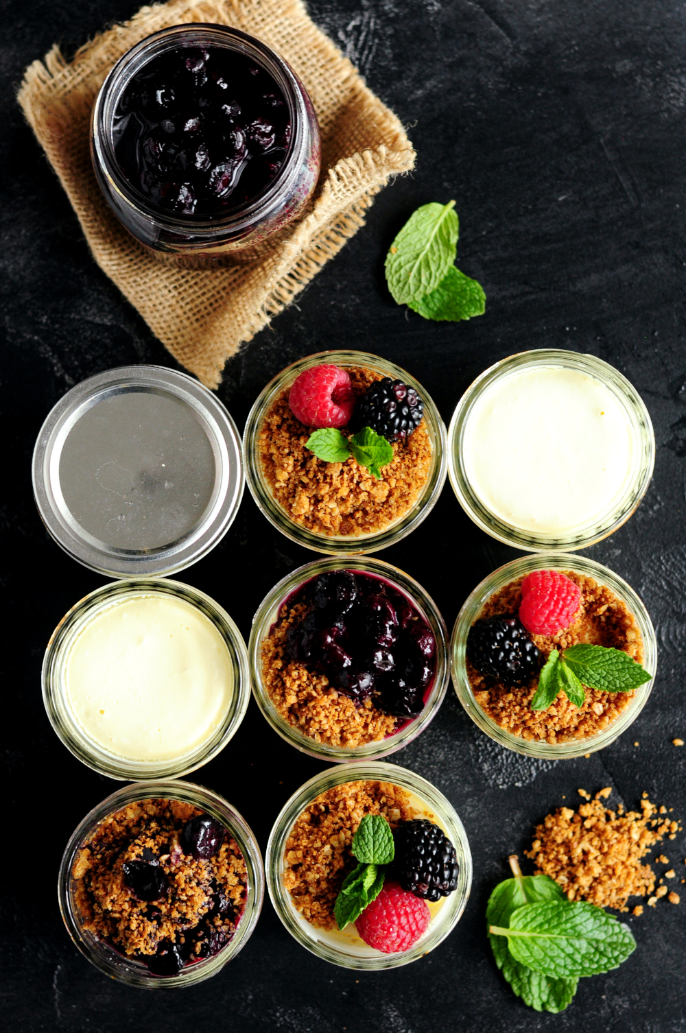 Sous vide cheesecake in jars with crust on top and fresh fruit toppings and blueberry toppings