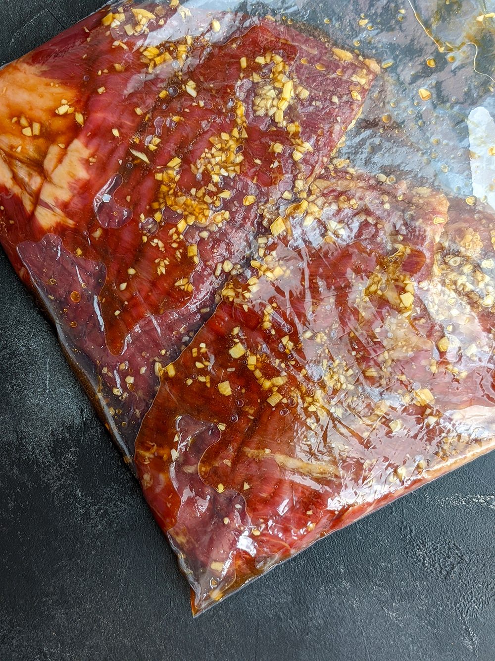 Place the flank steak and the marinade (coconut aminos, garlic, ginger, and sesame oil) in a large Ziploc bag or vacuum sealer bag (cut the steak in half to fit in the bag if necessary). Move the contents around and allow the steak to be well coated with the marinade. Arrange in a single layer, squeeze the air out with your hands, and seal. Refrigerate and marinate for at least 2 hours or overnight. (You may also skip the marinating time and directly move on to the next step.) 