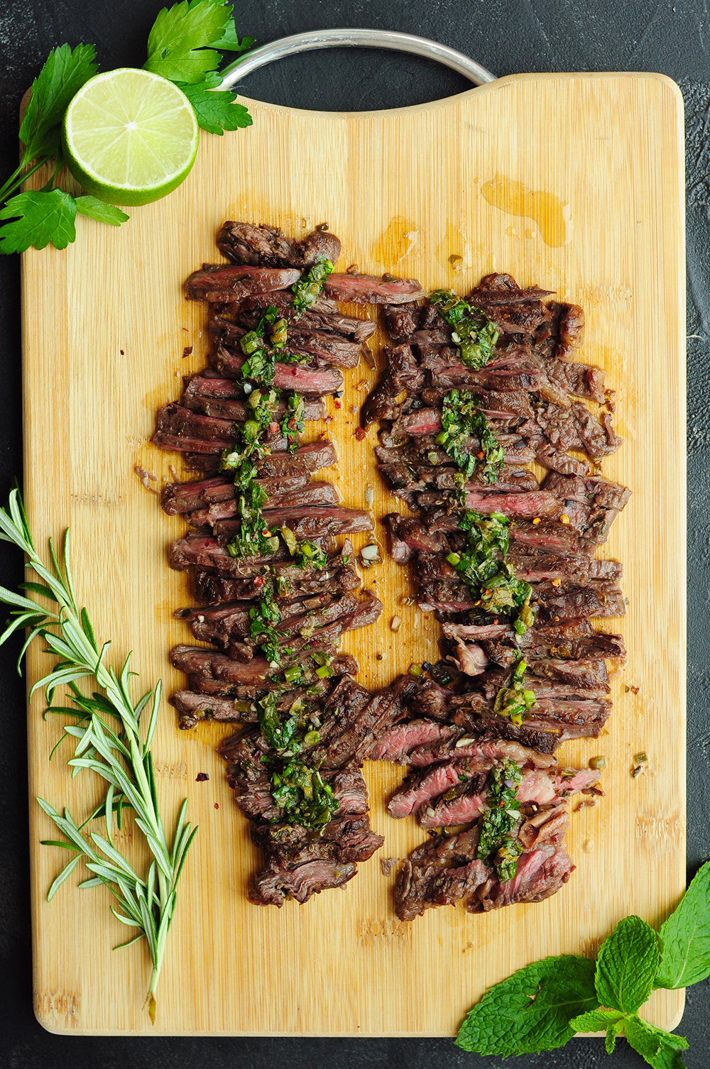 Sliced sous vide skirt steak with dressing on a cutting board