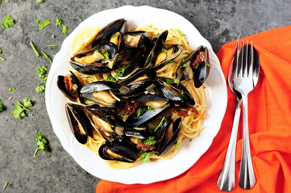 Super easy mussel recipe steamed in white wine and flavor-rich chicken bone broth. Serve it as an amazing appetizer or over spaghetti as an elegant dinner. 